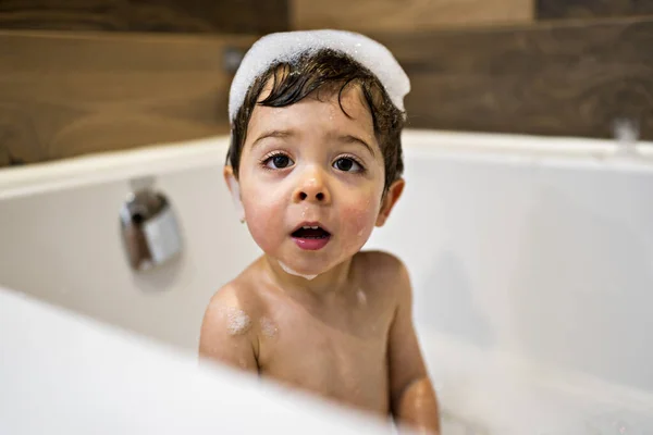 Happy two year kid bathes with toys in bath with foam — Photo