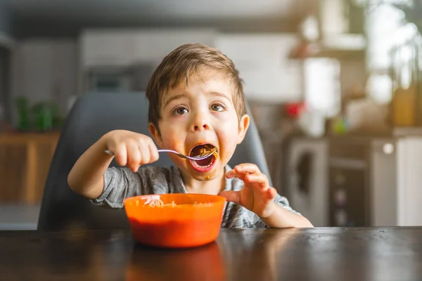 Kid eating spaghetti in the kitchen havinf fun — Photo