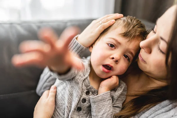 Hengiven mor krammer og trøster sin søn på sofaen - Stock-foto