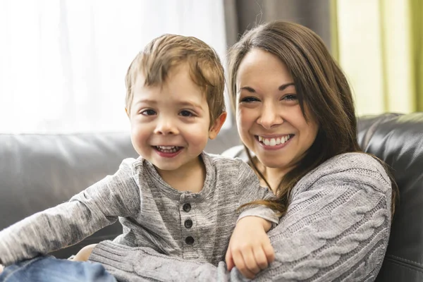 Портрет улыбающегося мальчика с матерью на диване — стоковое фото