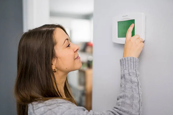 Kobieta ustawić termostat w domu. — Zdjęcie stockowe