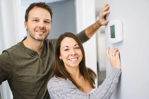 Nice couple set the thermostat at home — Stock Photo, Image