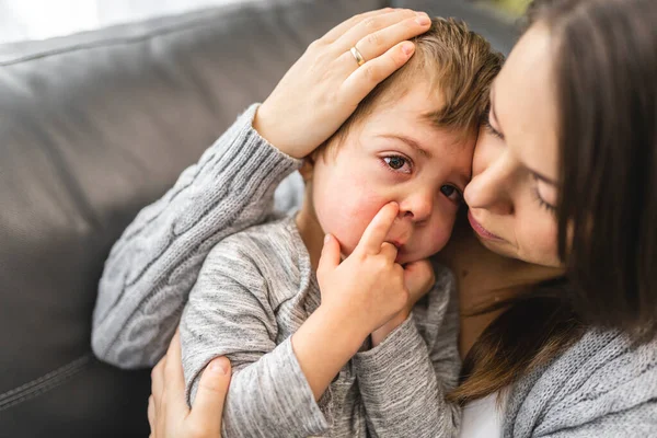 Devoted mother hugging and comforting her son on sofa — Stock Fotó