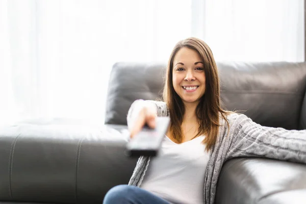 Mujer joven viendo la televisión tirada en el suelo en casa —  Fotos de Stock