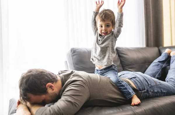 Unavený mladý otec s chlapcem na zádech koncept hyperaktivních dětí a unavených rodičů — Stock fotografie