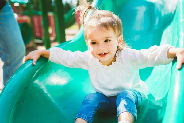 Two years old girl in playground equipment play on slide — Stock fotografie