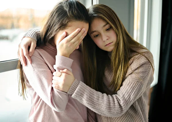 Teenage girl consoling her sad friend on her bedroom — стоковое фото