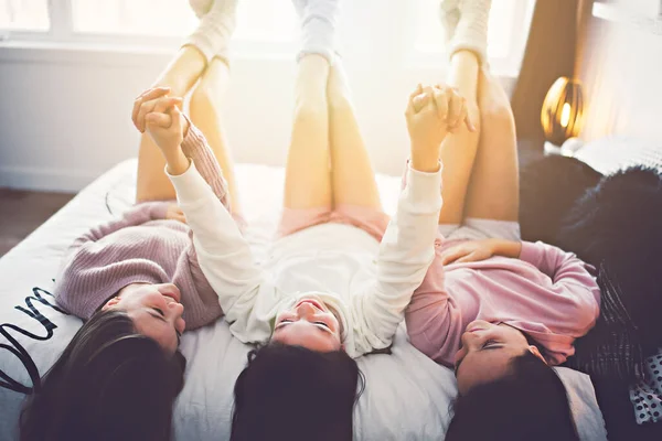 Three excited teenager girls having fun together enjoying laze leisure time on bed — Zdjęcie stockowe