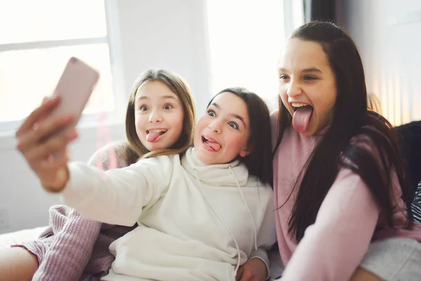 Teen friends girls with smartphone taking selfie at home — стоковое фото