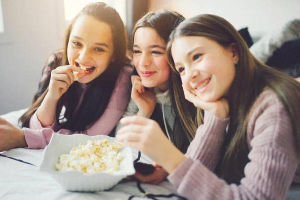 A pajama party with teens eat popcorn on the bed — Photo