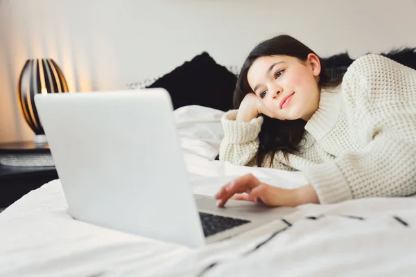 Leuk tiener meisje met behulp van een computer in haar slaapkamer. — Stockfoto