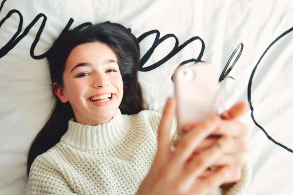 Ένα έφηβο κορίτσι με smartphone στο κρεβάτι — Φωτογραφία Αρχείου