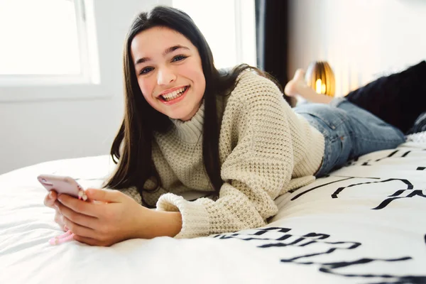 Uma adolescente com smartphone na cama — Fotografia de Stock