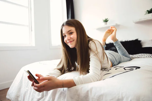A teenage girl with smartphone on bed — Photo