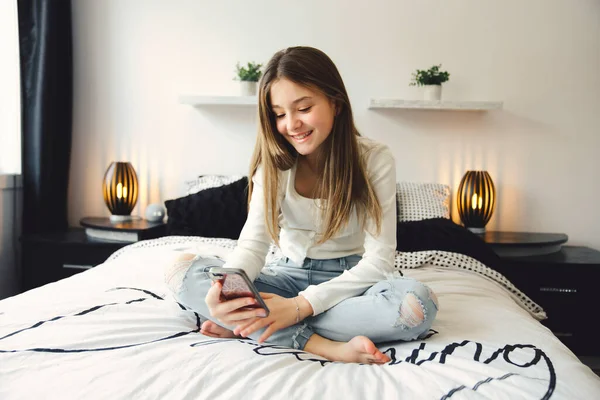 Uma adolescente com smartphone na cama — Fotografia de Stock
