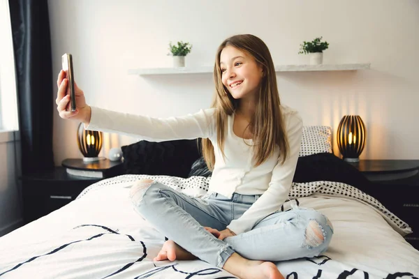A teenage girl with smartphone on bed — Photo