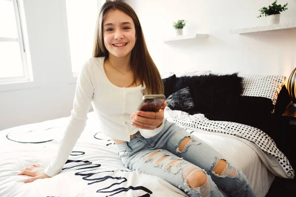 Una adolescente con smartphone en la cama — Foto de Stock