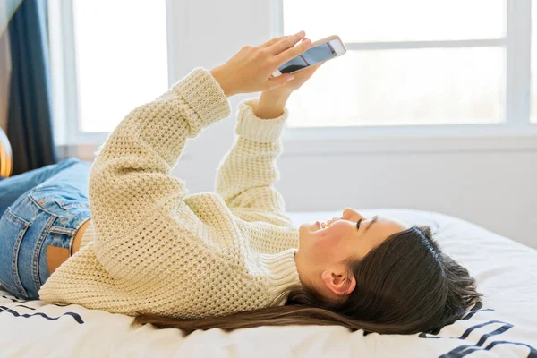 A teenage girl with smartphone on bed — ストック写真