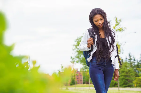 A black adult woman university student on campus with backpack — Stockfoto