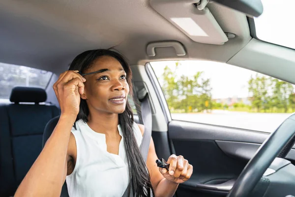 Black woman driver seated in her new car holding make up — Photo