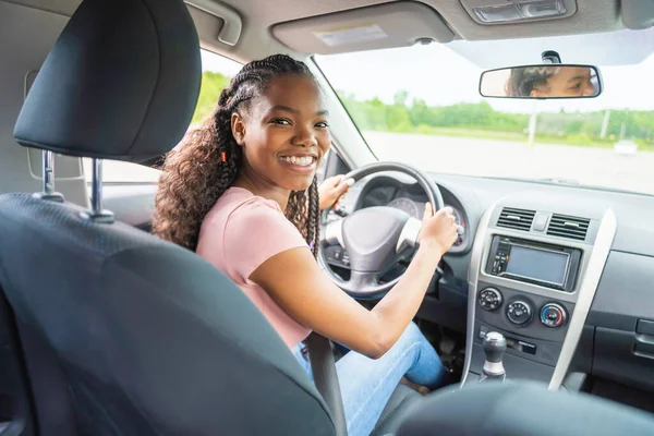 Young black teenage driver seated in her new car