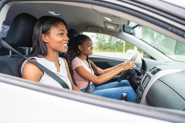 Young black teenage driver seated in her new car with her mother — 스톡 사진