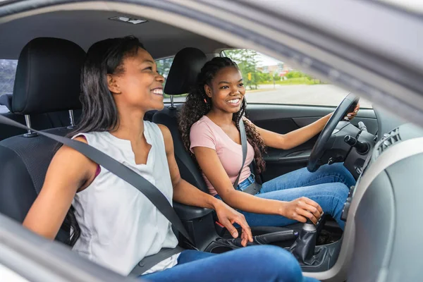 Young black teenage driver seated in her new car with her mother — 스톡 사진