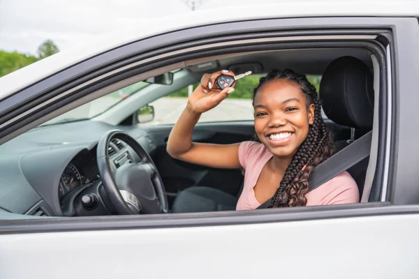 Young black teenage driver seated in her new car