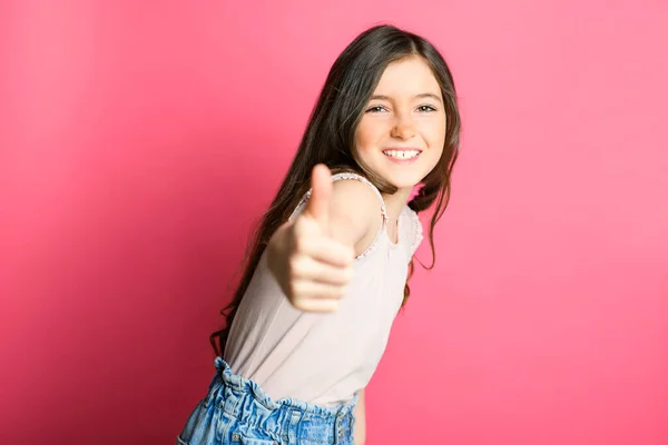Bonito positivo polegar up criança sobre rosa backgroud no estúdio — Fotografia de Stock