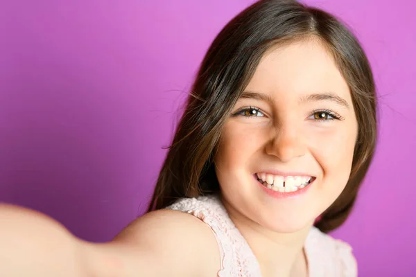 Schattig kind met dungarees over paarse achtergrond op studio doen selfie — Stockfoto