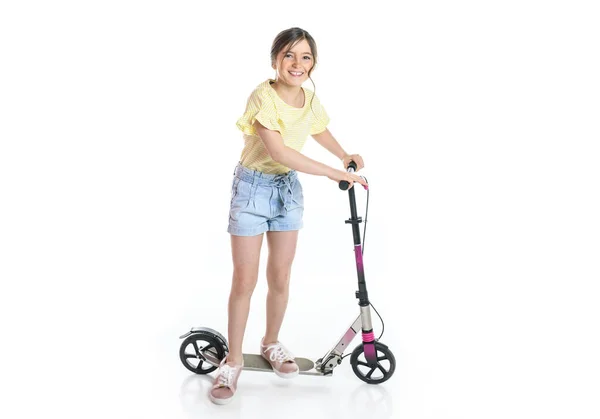 Felice bambina cavalcando il suo scooter isolato su bianco . — Foto Stock