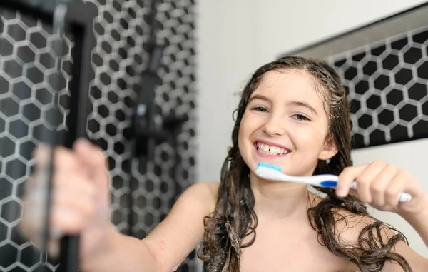 Beautiful girl bathing under a shower with toothbrush at home — стоковое фото