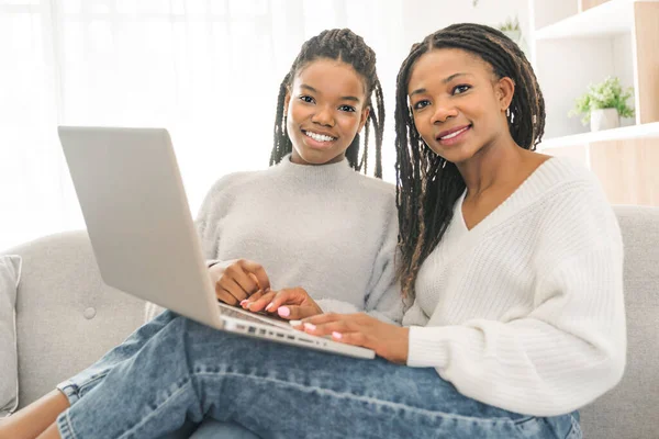Mother and daughter sitting on sofa at home with laptop — Photo