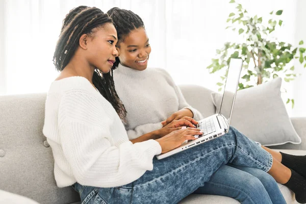 Mor och dotter sitter på soffan hemma med laptop — Stockfoto