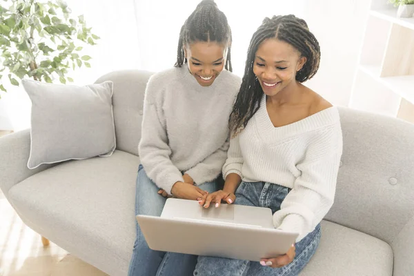Mor och dotter sitter på soffan hemma med laptop — Stockfoto