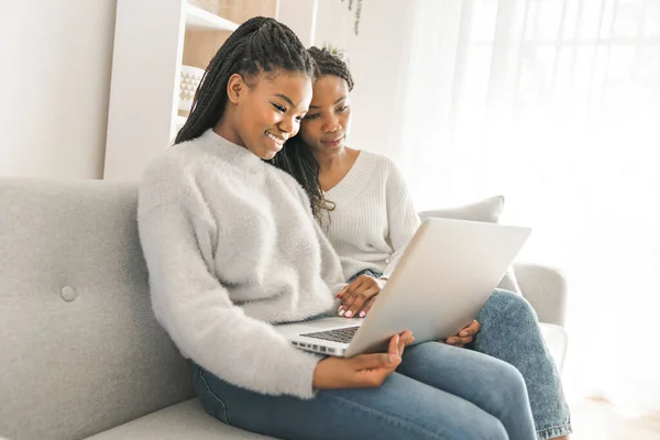 Mor och dotter sitter på soffan hemma med laptop — Stockfoto