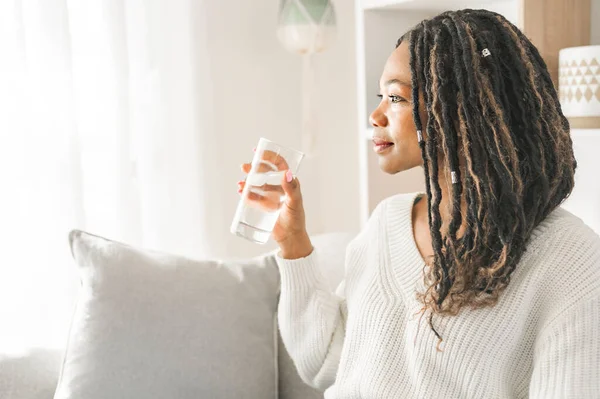 En avslappnad leende kvinna dricker lite vatten hemma — Stockfoto