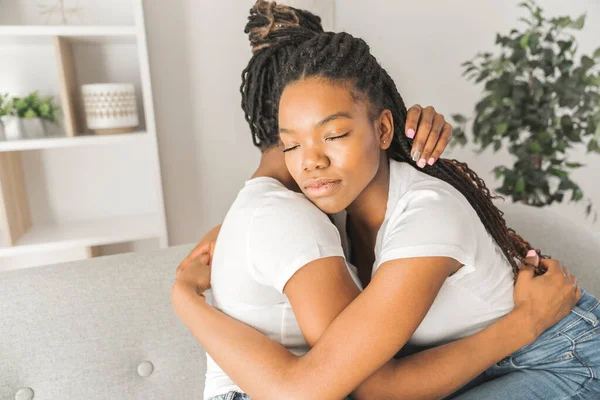 Mother and daughter consoling on sofa at home