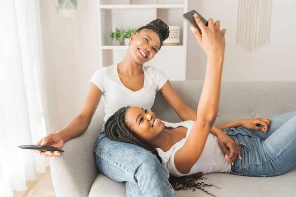 Mor och dotter sitter på soffan hemma och tar selfie med mobiltelefon — Stockfoto