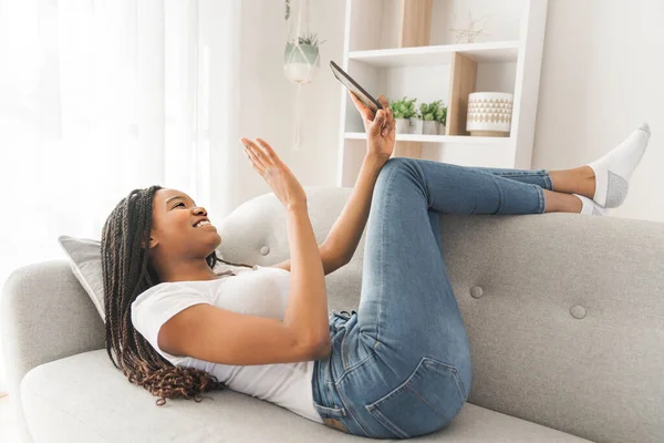 Young African American teen on a sofa in her living room using cellphone — Stockfoto