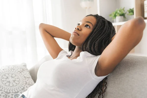 Young African American teen on a sofa in her living room relaxing — Stockfoto