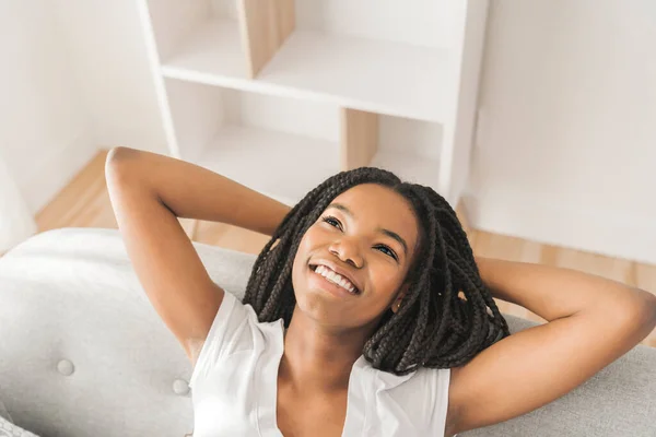 Young African American teen on a sofa in her living room relaxing — Stok fotoğraf