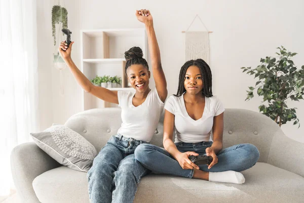 Mother and daughter sitting on sofa at home play video game together — Stockfoto