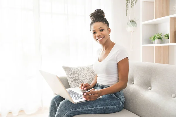Portrait of A African Woman sit on the sofa at home using laptop — Stockfoto