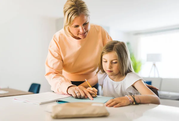 Mom helping kid with homework at home — стокове фото