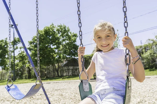 Active little girl having fun on playground on the summer time on the swing — Foto de Stock