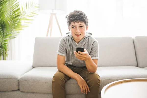 Giovane adolescente seduto sul divano utilizzando un telecomando — Foto Stock
