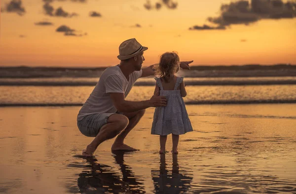 Ευτυχισμένη οικογένεια στην παραλία ένας πατέρας και μια κόρη διασκεδάζουν το ηλιοβασίλεμα — Φωτογραφία Αρχείου