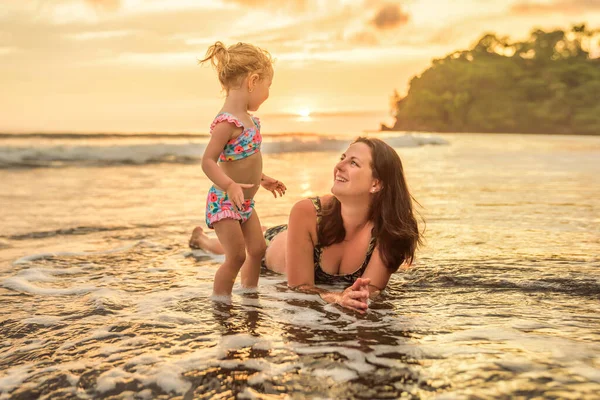 Ευτυχισμένη οικογένεια στην παραλία, μητέρα, παιδί, κόρη, να διασκεδάζει το ηλιοβασίλεμα. — Φωτογραφία Αρχείου