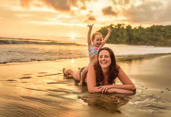 Ευτυχισμένη οικογένεια στην παραλία, μητέρα, παιδί, κόρη, να διασκεδάζει το ηλιοβασίλεμα. — Φωτογραφία Αρχείου